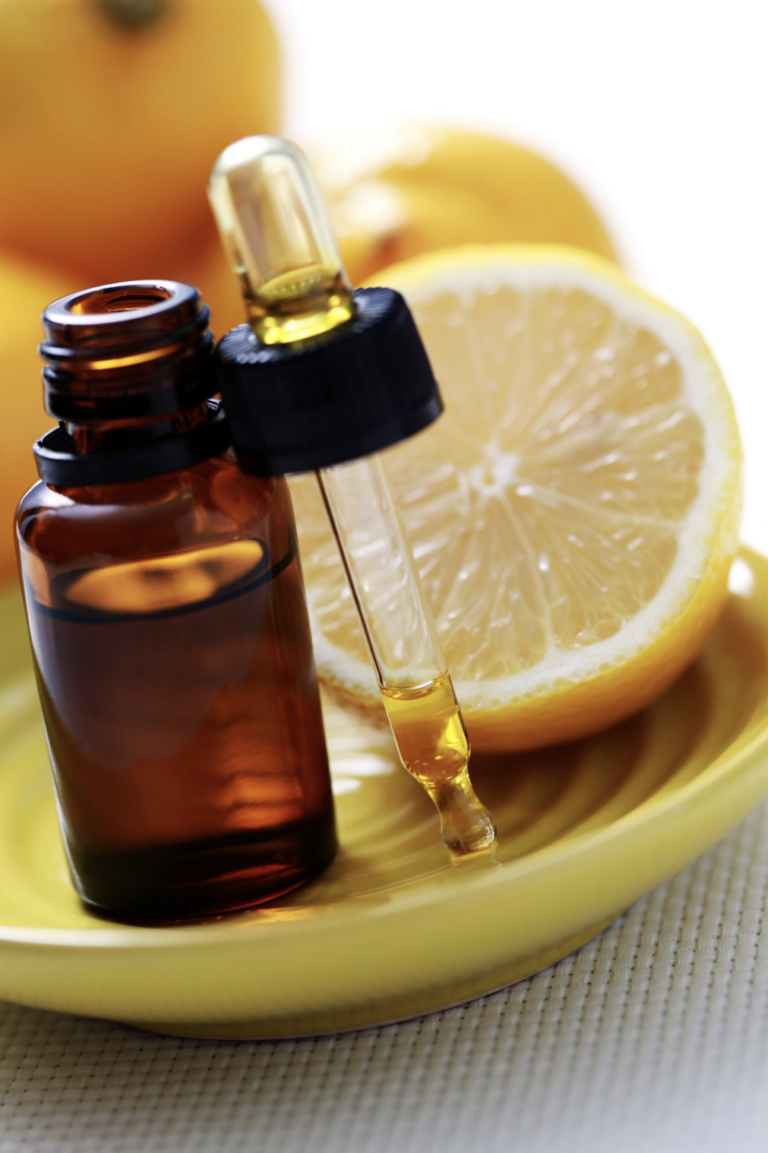 lemon essential oil in dropper on plate with fresh lemon